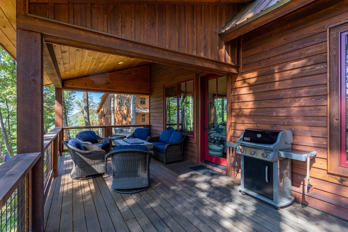 An inviting outdoor seating area with a grill, surrounded by trees and greenery, perfect for barbecues and social gatherings. The area is spacious and set up for group dining and relaxation in nature.