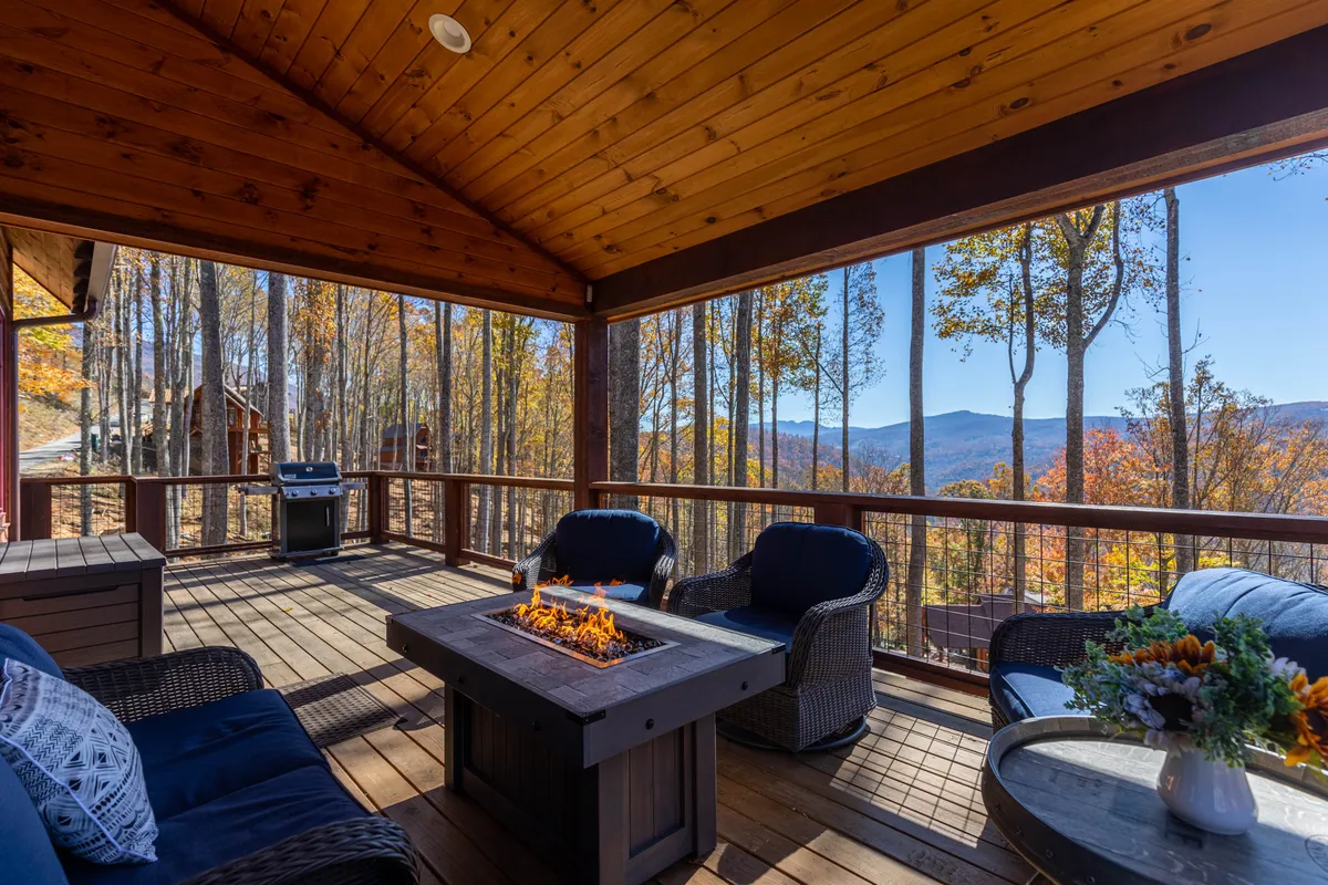 An inviting fire pit area with comfortable seating surrounded by nature. The fire pit is encircled by chairs, with mountains and trees in the background, highlighting a cozy spot to unwind after outdoor adventures.