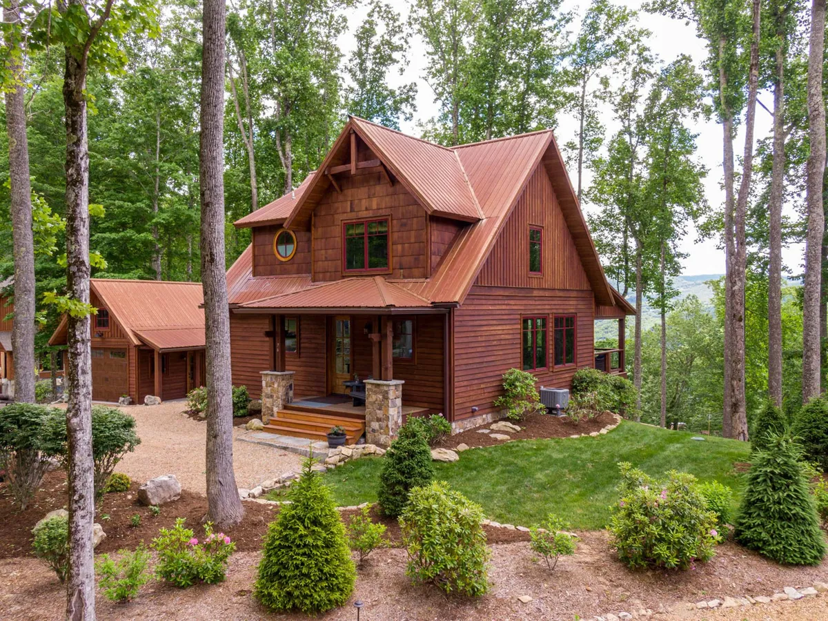 A welcoming view of the wooden house, stone steps, and lush greenery, suggesting easy access to nature trails and outdoor activities right from the property. The tranquil setting is inviting for both active adventures and peaceful relaxation.