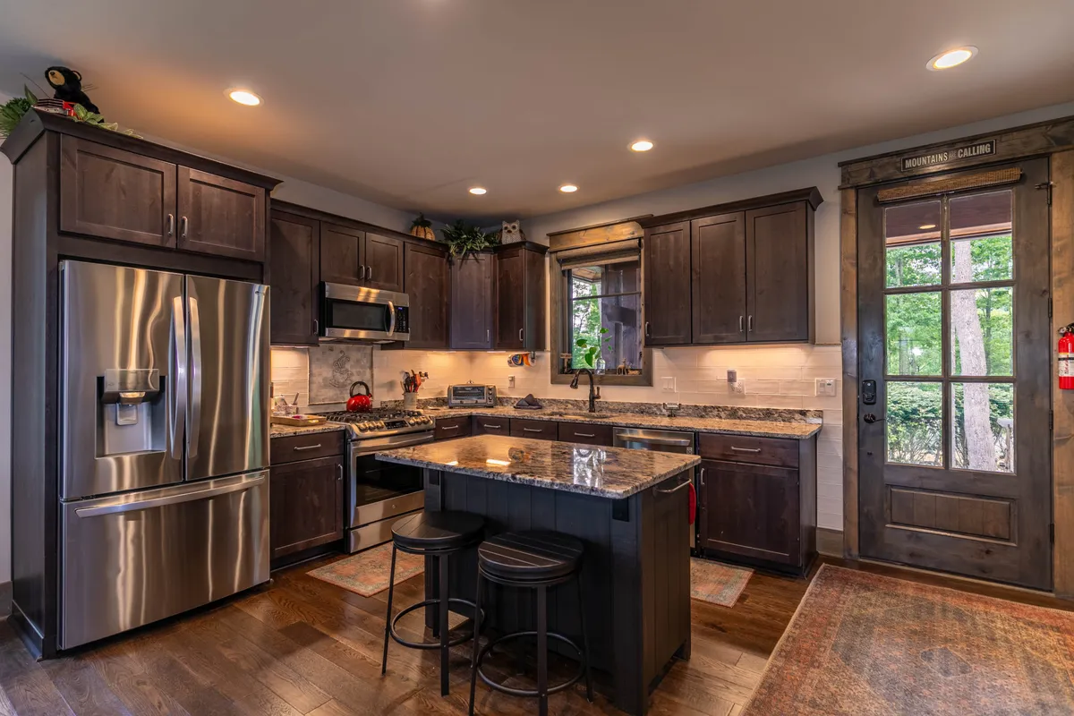 A warm, inviting kitchen featuring granite countertops, a spacious island, stainless steel appliances, and wooden cabinets. The layout encourages cooking and socializing, with the kitchen island providing ample space for meal prep or casual chat.